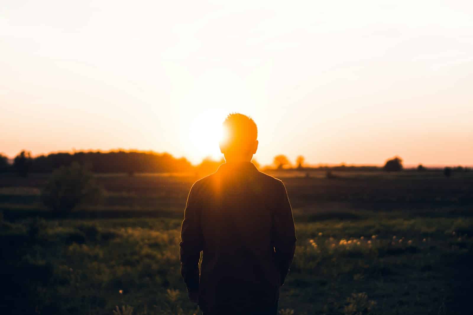 silhouette of man facing sunset