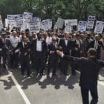 men in suit walking on street holding signages