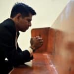 man sitting, closing his eyes and praying