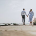 couple holding hands with standing on shore